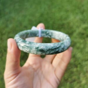 A hand holding Green Jade bangle