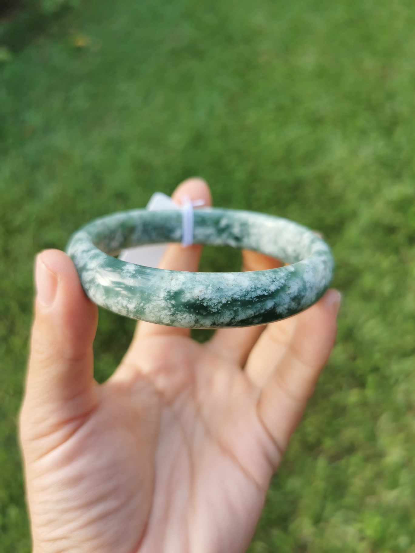 A hand holding Green Jade bangle