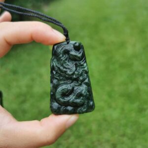 a hand holding a necklace Jade Dragon Pendant