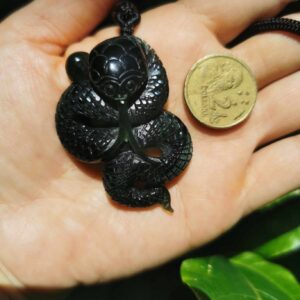A hand holding Jade Snake with coin as comparison