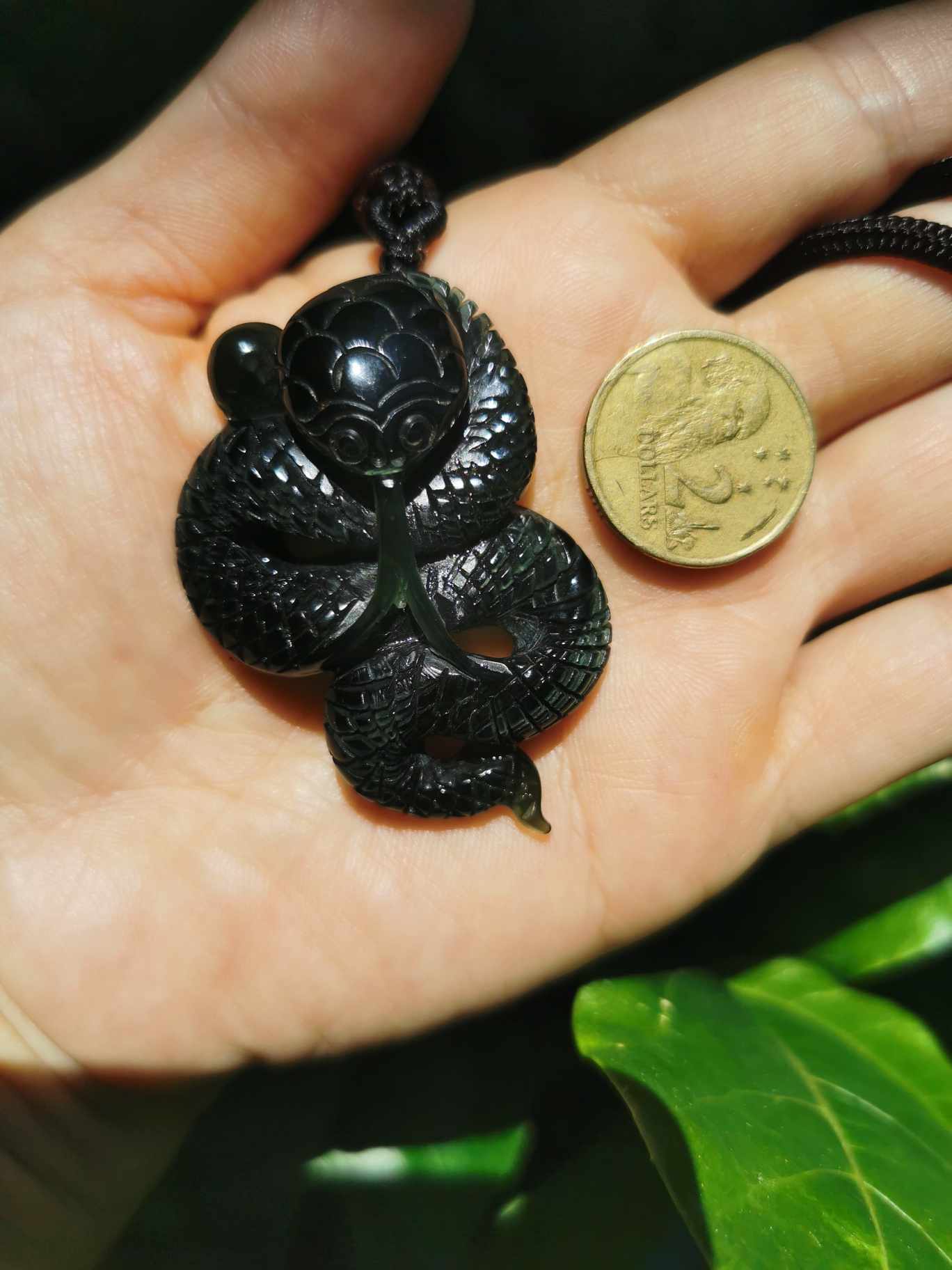 A hand holding Jade Snake with coin as comparison