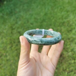 A hand holding Green Jade bangle